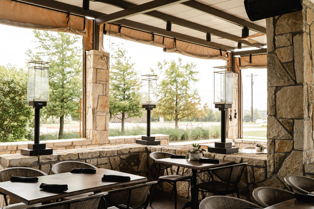 outdoor restaurant seating with stone wall, heat lamps and covered openings