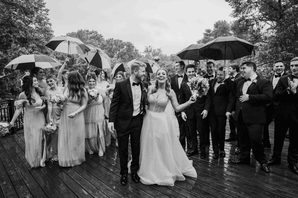 Bride and groom walk in the rain with their wedding party