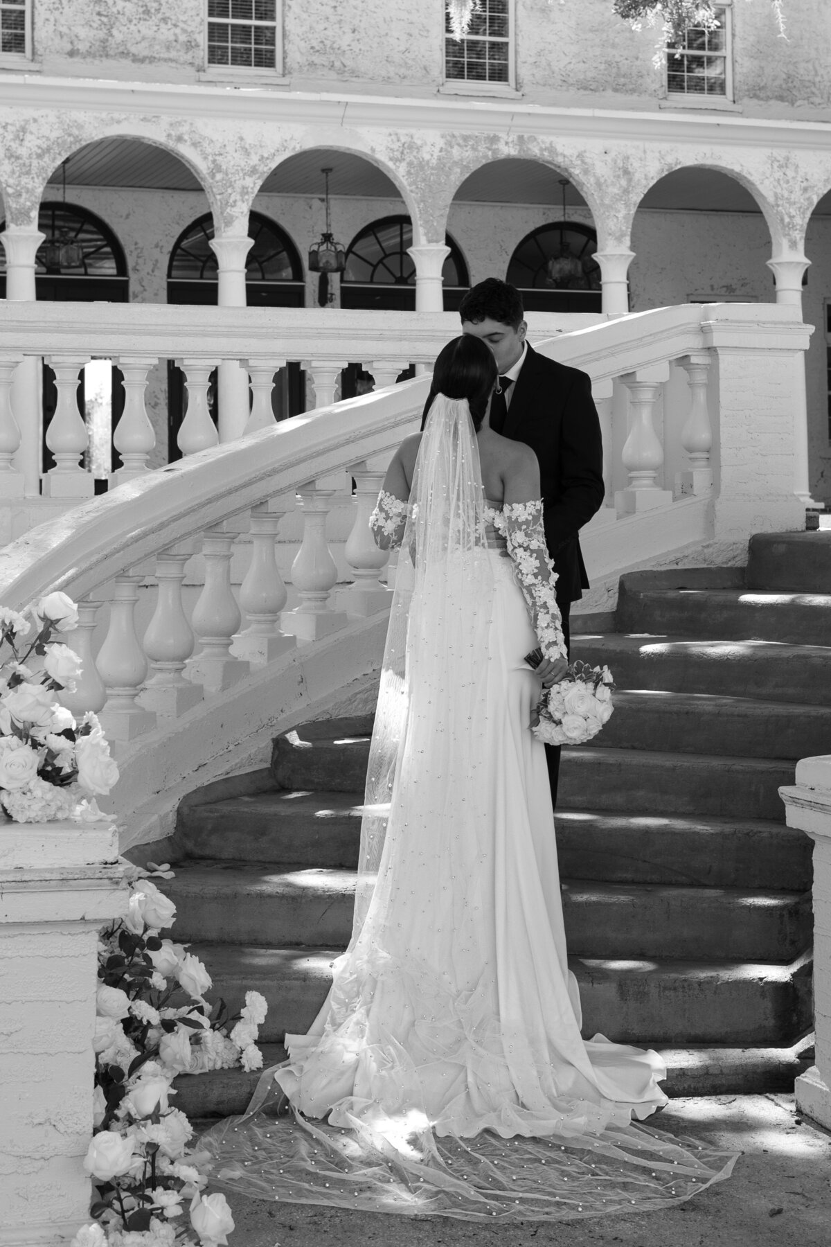 Bride and groom posing at the steps of Bella Cosa wedding venue