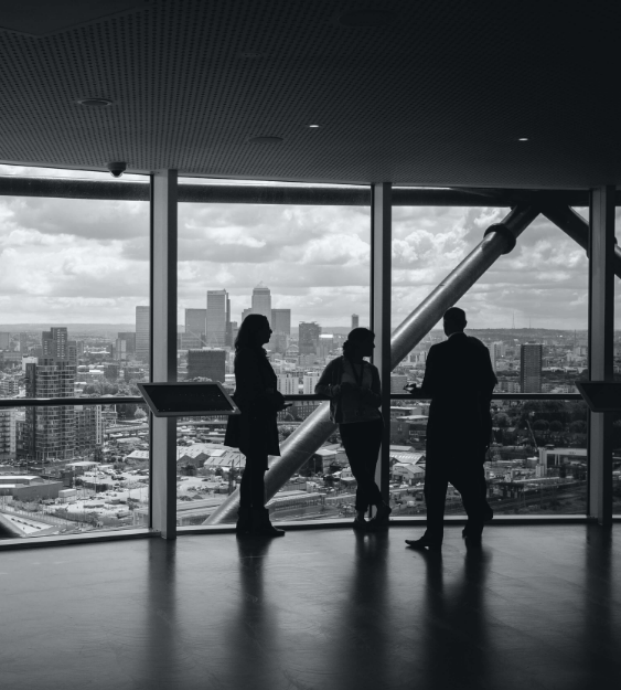 black and white photo of people talking in city office with skyline of the city