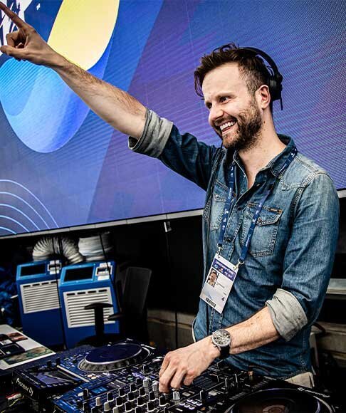 Smiling DJ raising arm while performing at Australian Open, creating high-energy atmosphere