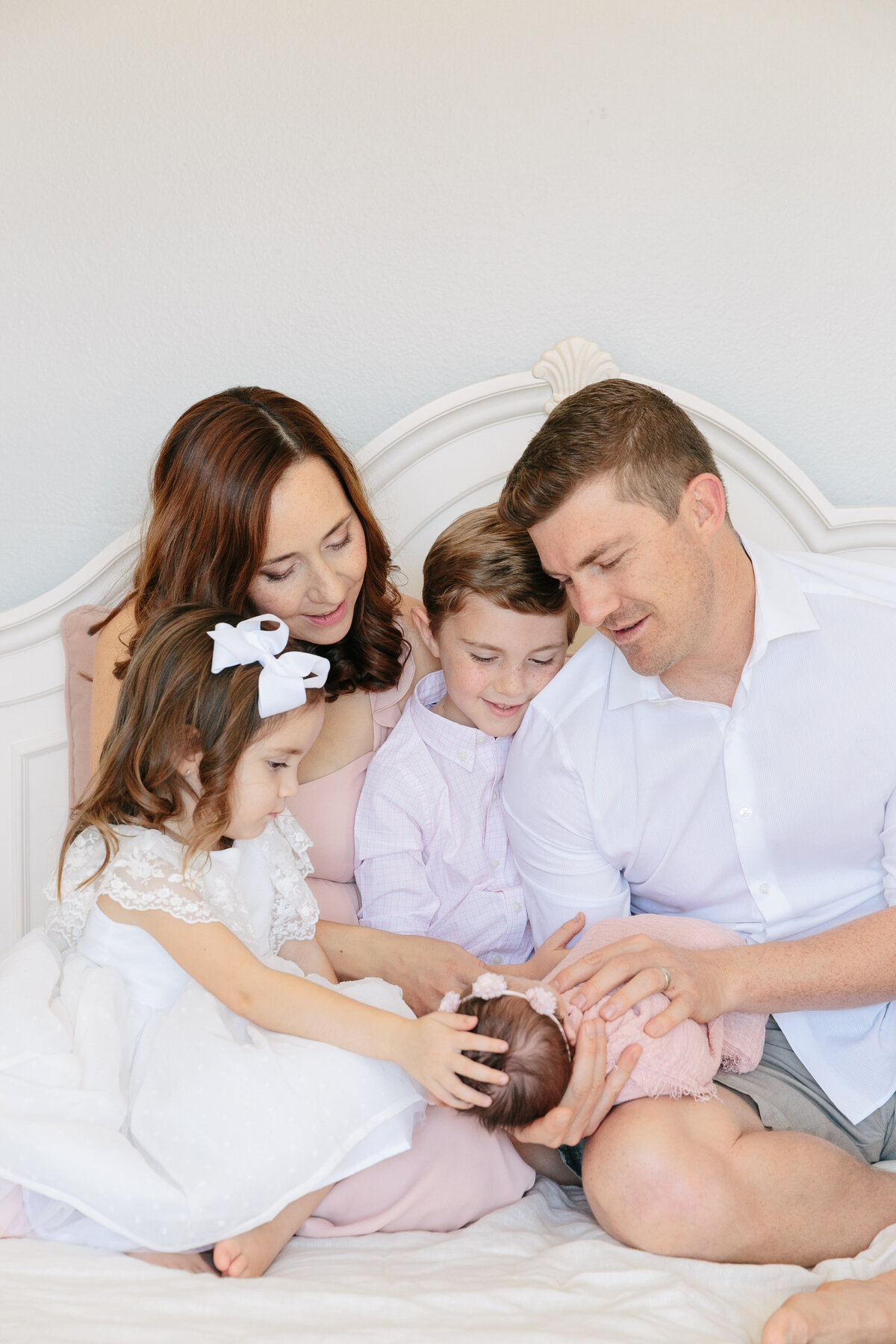 A family sitting on a bed looking down at a newborn child