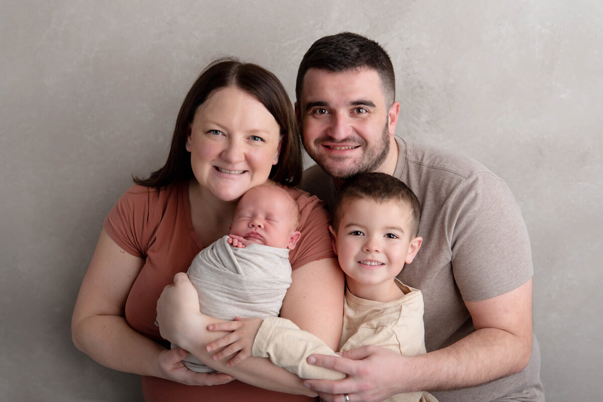 Family newborn photography session with mom and dad and big brother all in neutrals.