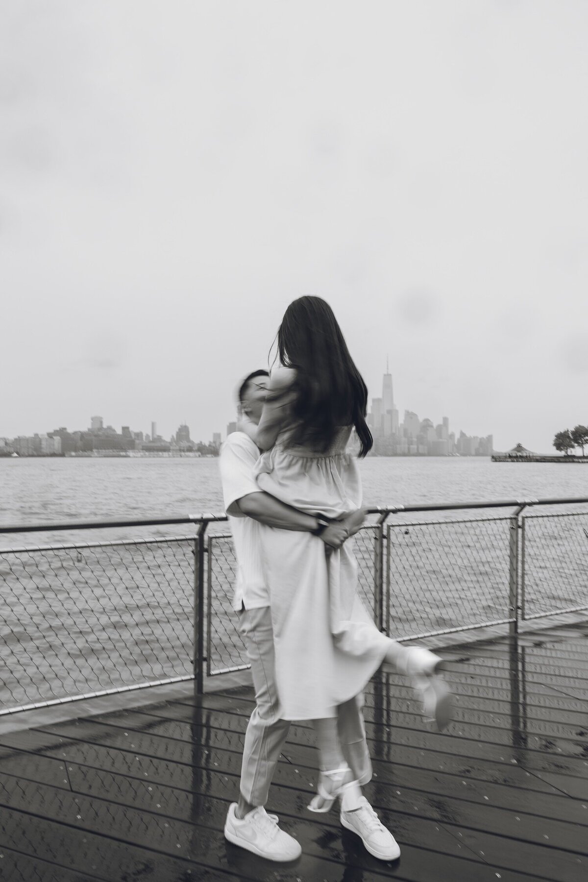 Couple embracing on a Hoboken pier with NYC skyline in background