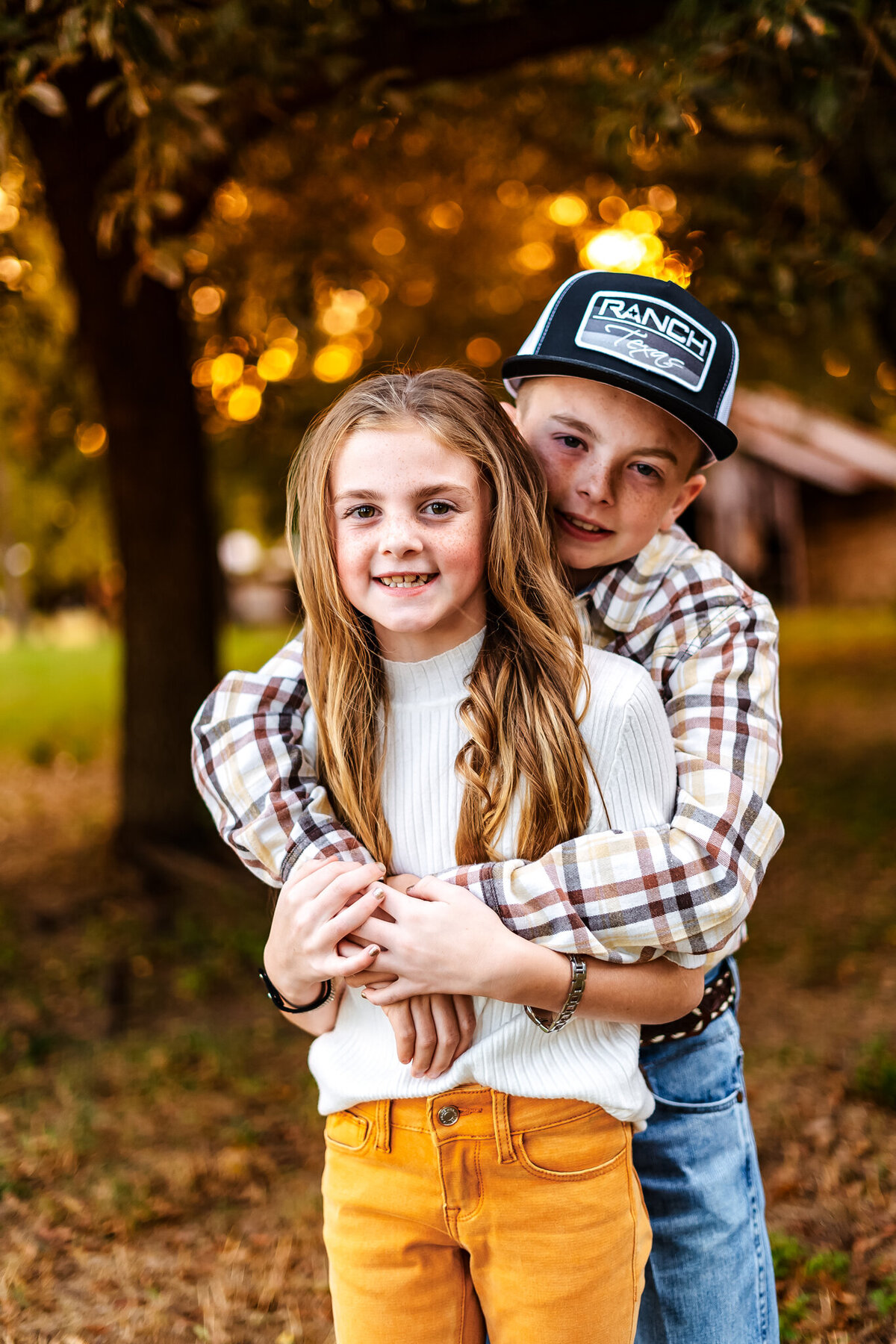 Brother hugs sister infront of a barn at sunset in Gladewater, Texas