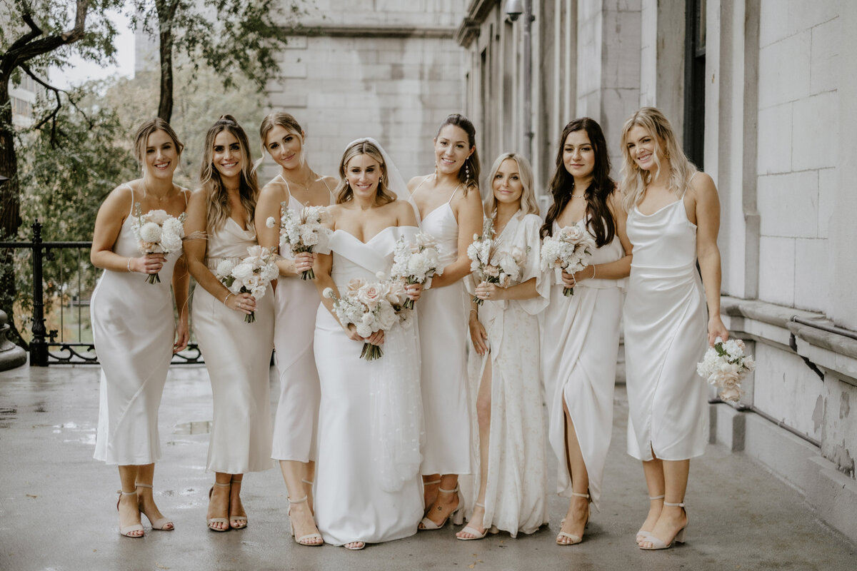 A bride and her bridesmaids hold bouquets of white flowers in Old Montreal.