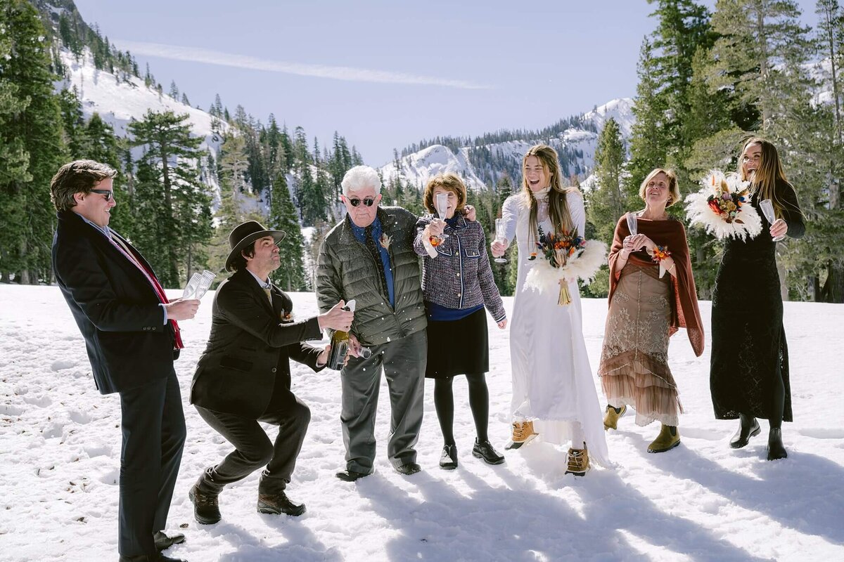 Champagne toast with family during a winter elopement with backdrop view of snowy Alpine Meadows behind.