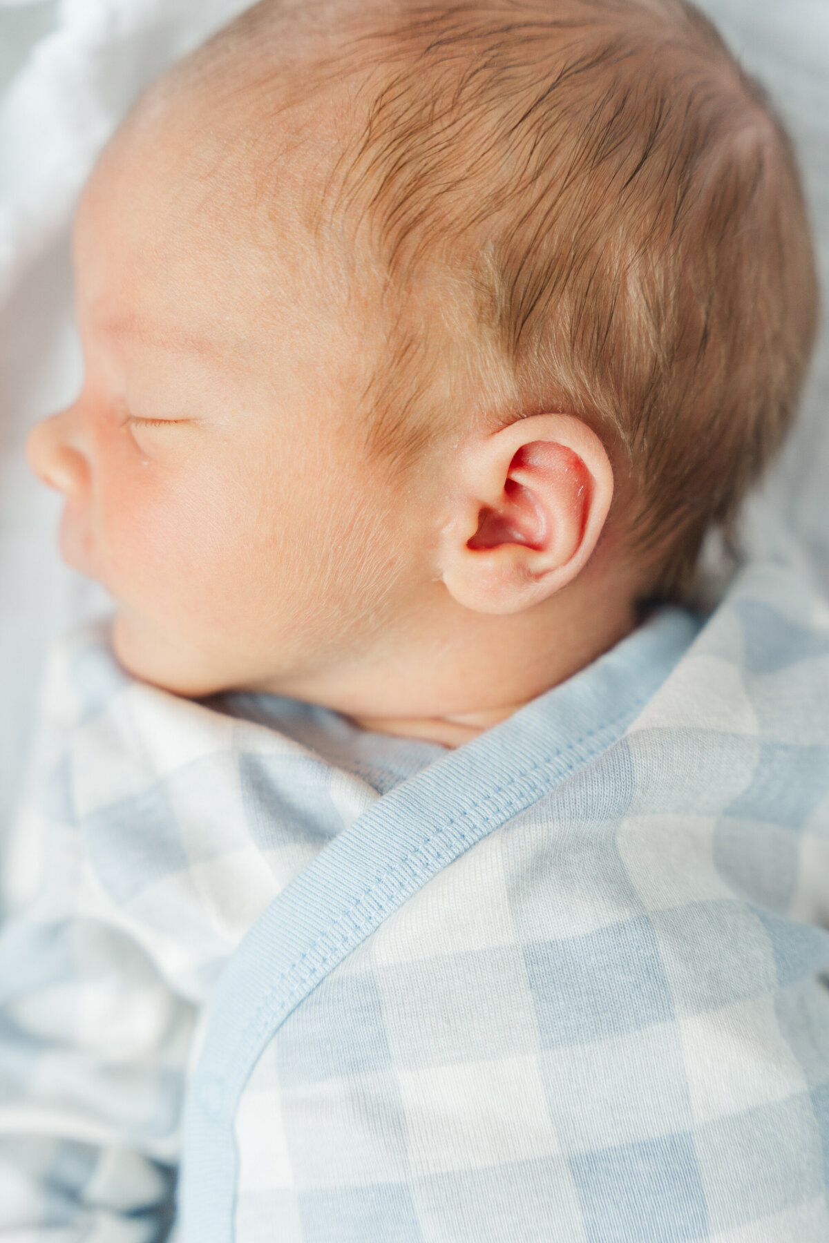 Close-up of a newborn baby's delicate profile, highlighting their tiny nose, soft lips, and wispy hair