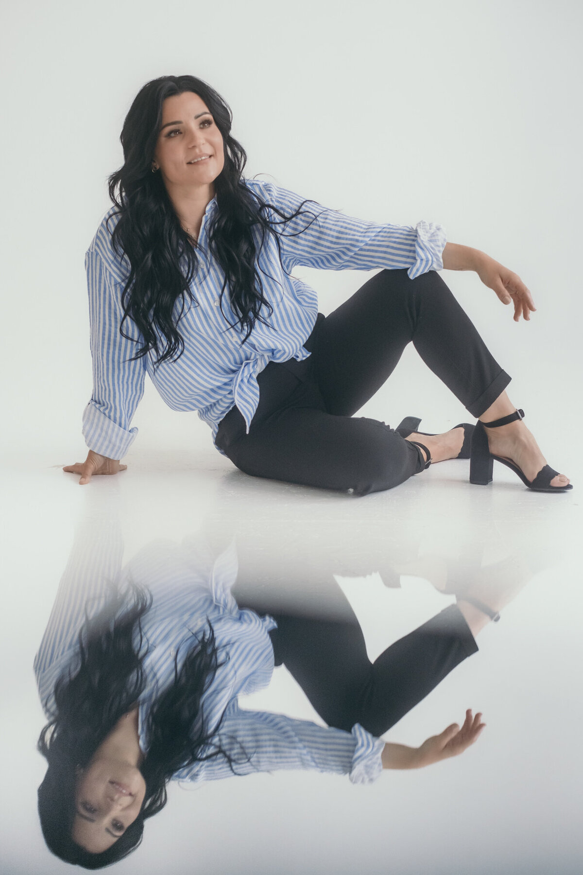 Woman sitting on the floor and smiling, with a mirror effect – creative portrait photography