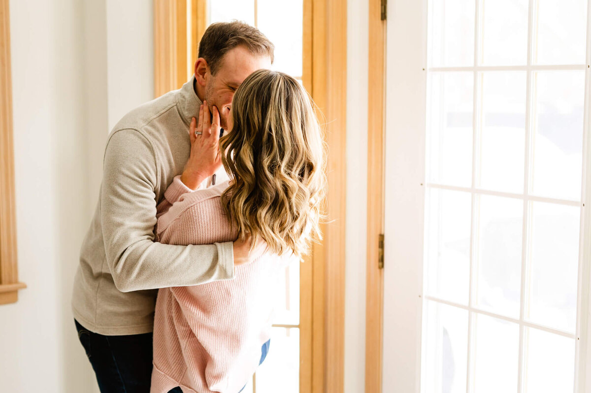 Couple kissing next to window during in home photography session in Naperville, IL.