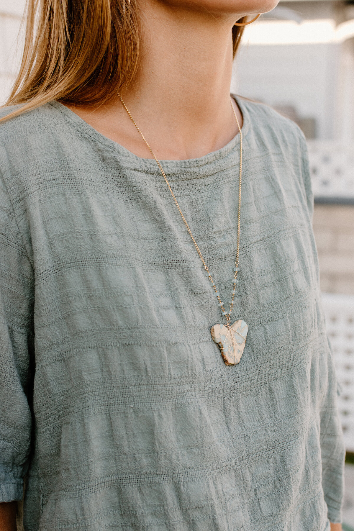 stone necklace on sage colored shirt