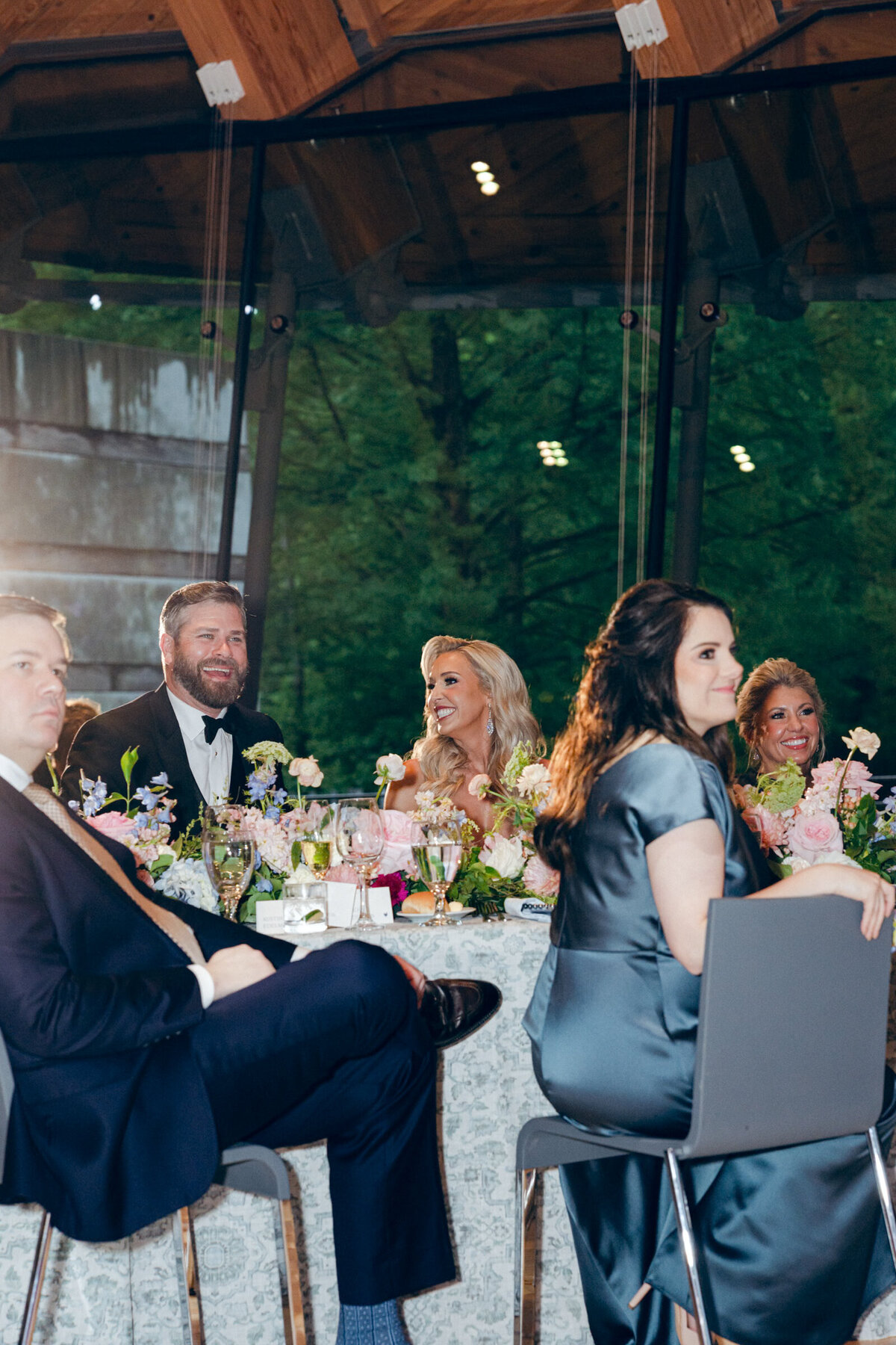 A candid wedding photo of the bride and groom during speeches during their wedding reception at Crystal Bridges Museum of American Art