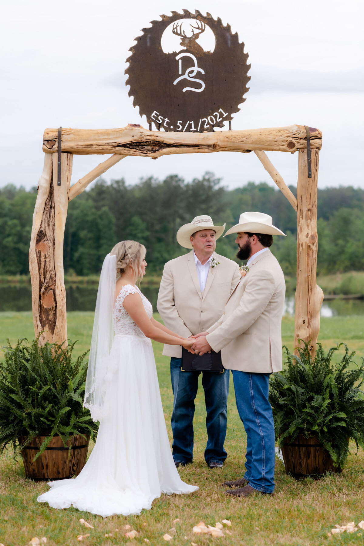 outdoor wedding ceremony with bride and groom holding hands at the alter with their officiant captured by Little Rock wedding photographer