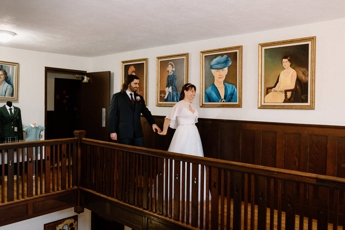 A bride leads the groom along the corridor of their wedding venue
