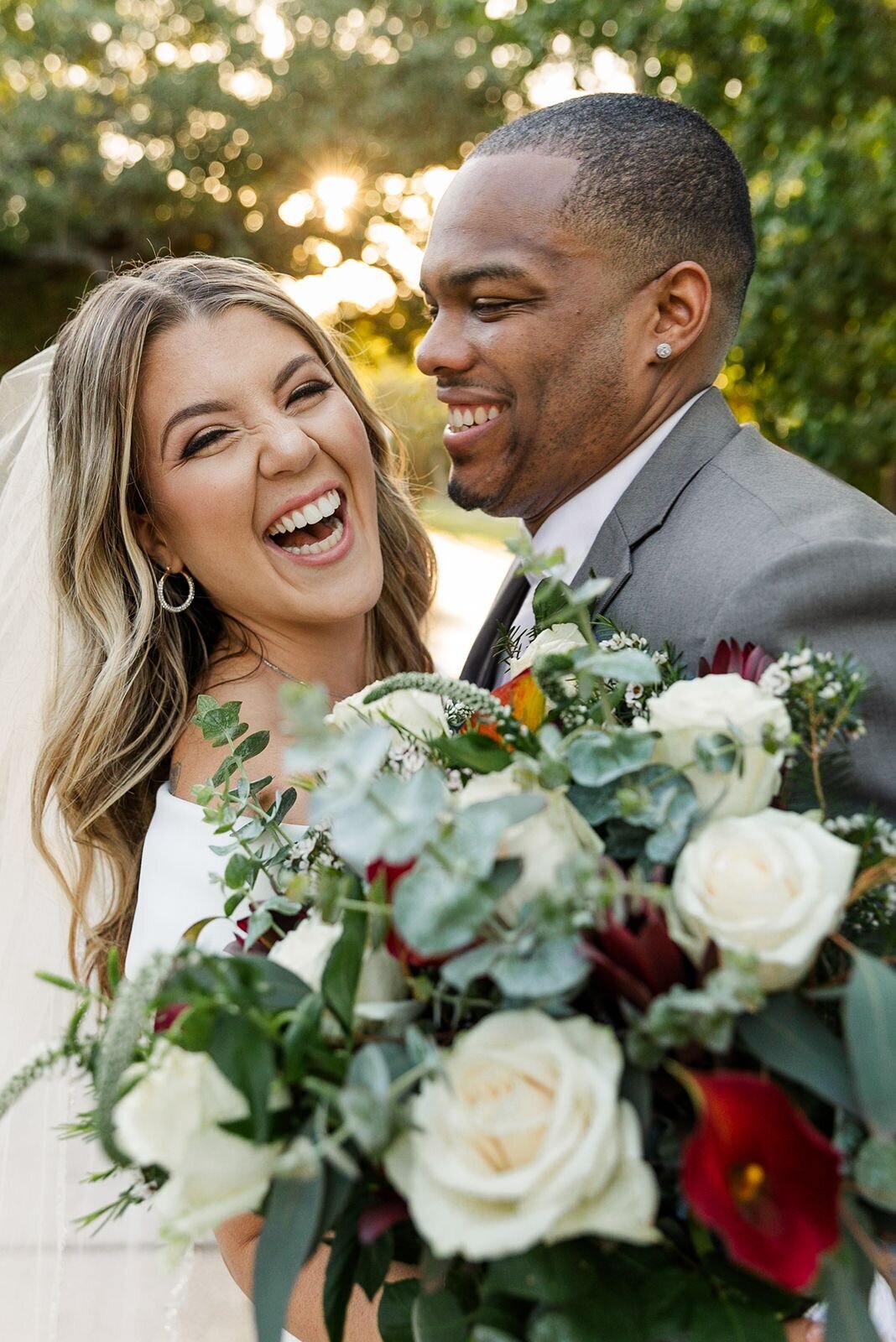 Bride and groom laughing together during just married portraits