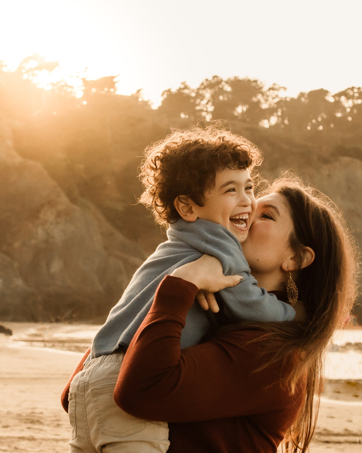 Portrait of Mother kissing autistic son's cheek. He smiles joyfully