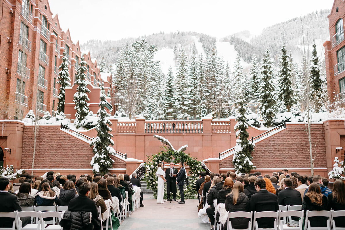 Wide shot image of the St. Regis outdoor  winter wedding ceremony with guests and bride and groom at the altar.