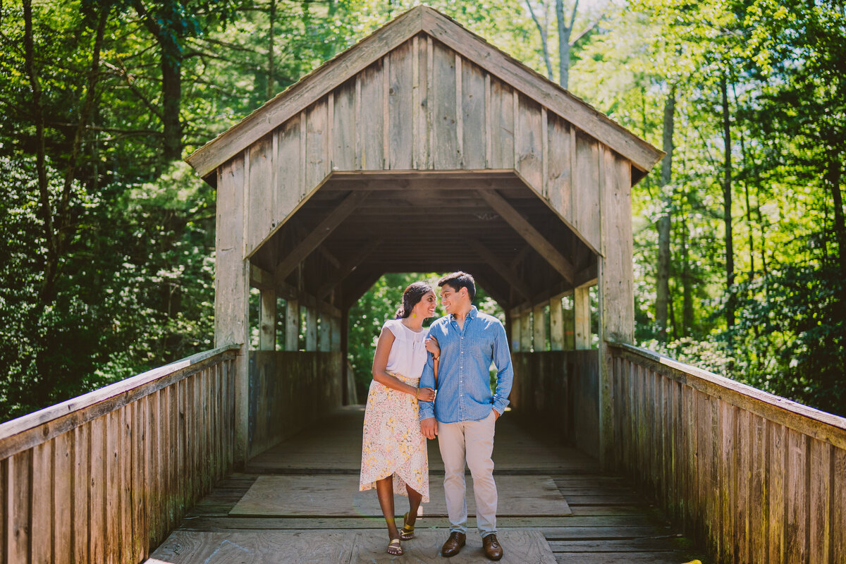 A couple standing at the entrance of a foot bridge at the devil's hopyard park in connecticut