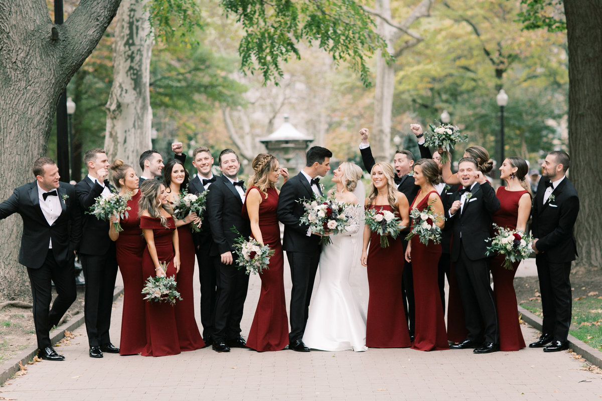 bridal party clapping and celebrating while bride and groom kiss
