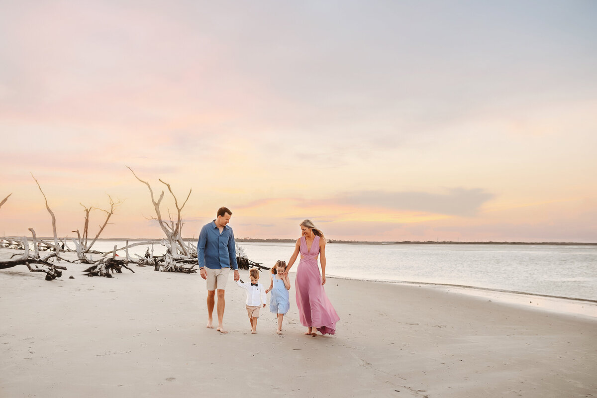 Parents walk along the beach with their small children during Family Photoshoot on Folly Beach.
