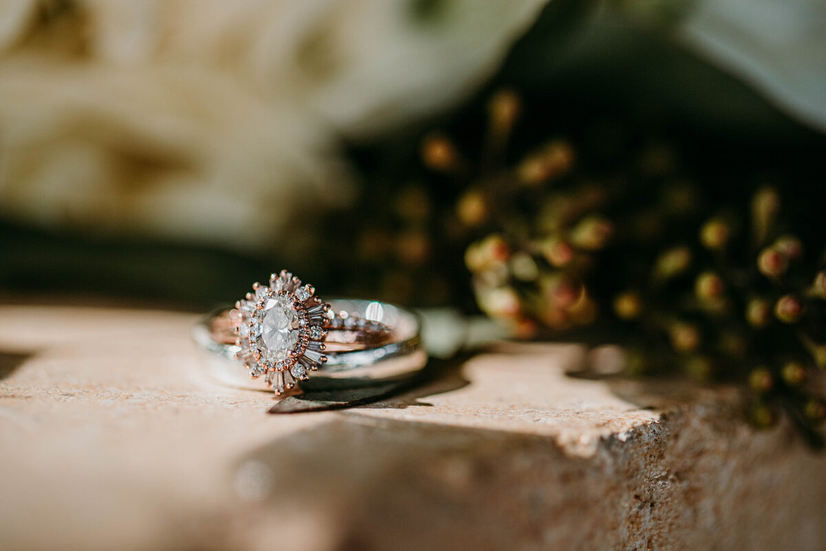 wedding and engagement rings in fron of bouquet