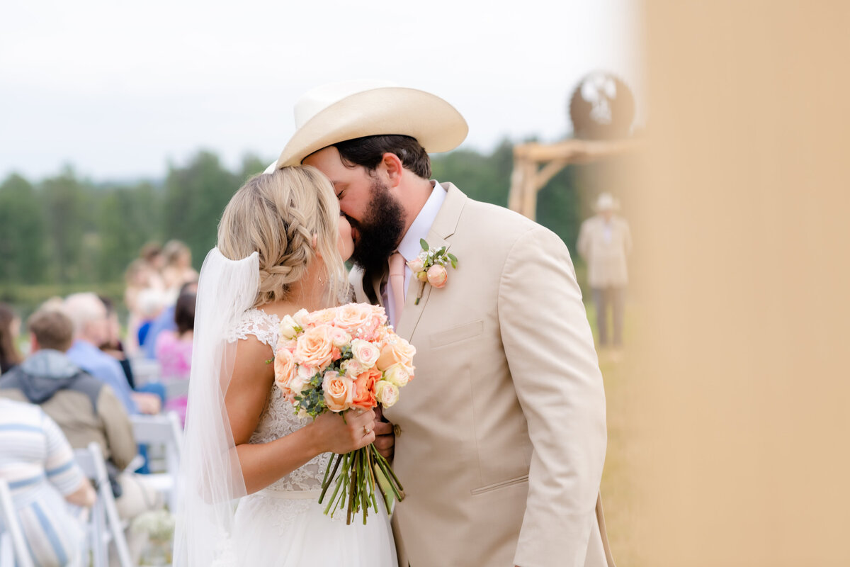 outdoor country wedding with bride and groom walking down the aisle and kissing at the end of the aisle before they leave their wedding