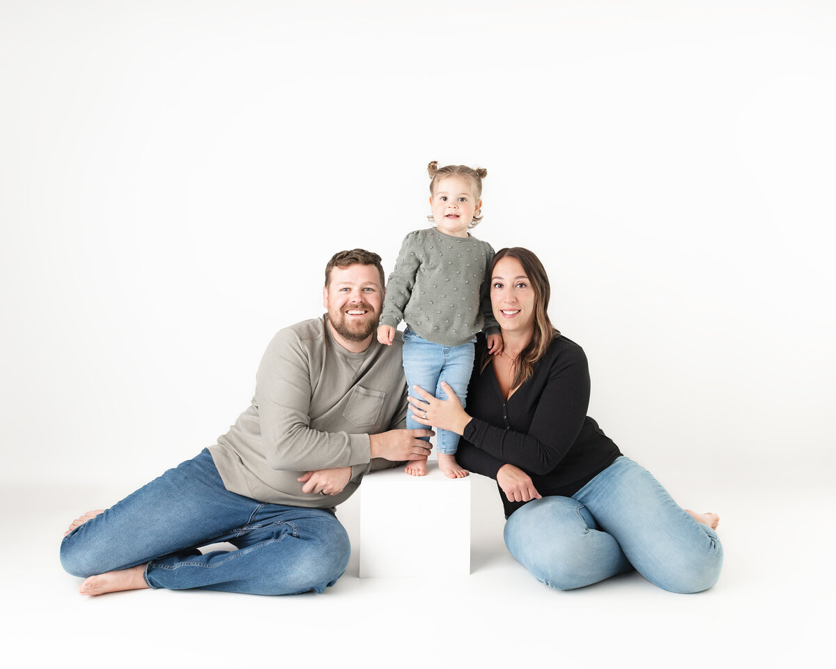 Studio family portrait with little girl posing between parents | Paris Ontario studio in Paris, Ontario