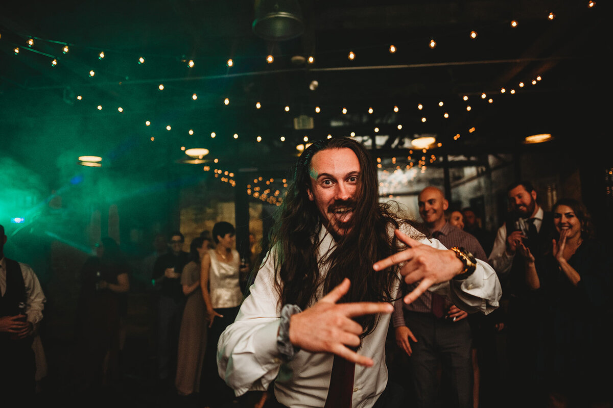 Baltimore wedding photographers captures Wedding guest dancing at an outdoor wedding reception with twinkle lights overhead and strobe lights
