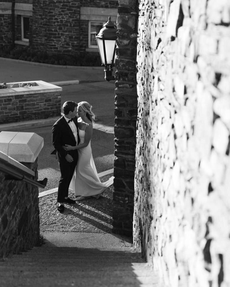 This stunning luxury photograph captures the bride and groom about to walk up the historic steps of the Banff Springs Hotel toward Castello's Italian Restaurant in Banff National Park. The grandeur of the hotel and the elegance of the moment highlight the timeless beauty of their special day.
