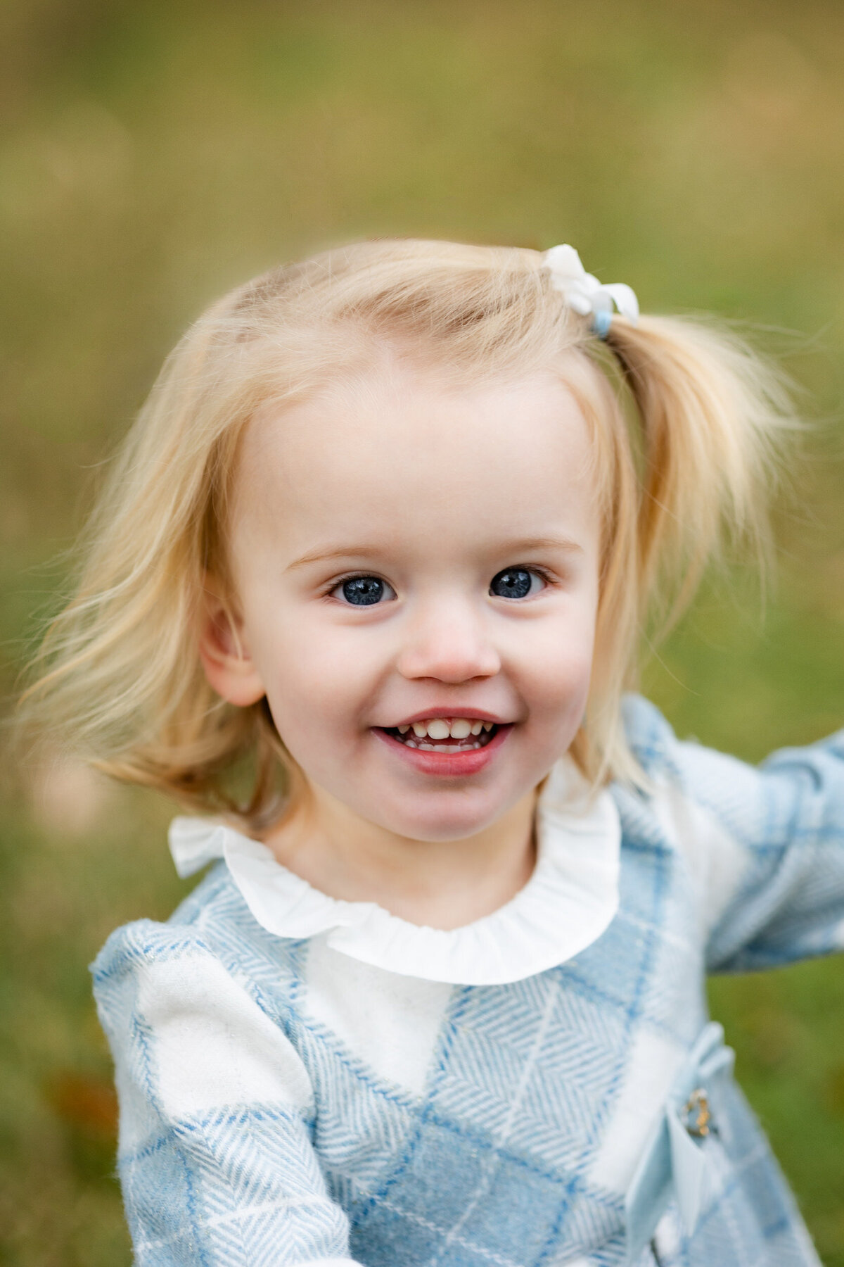 Close-up of a toddler girl smiling at the camera.