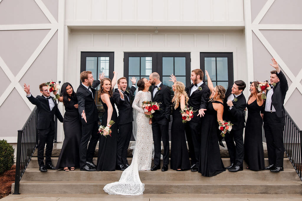 Bridal party in front of The Venue at Birchwood smiling and cheering