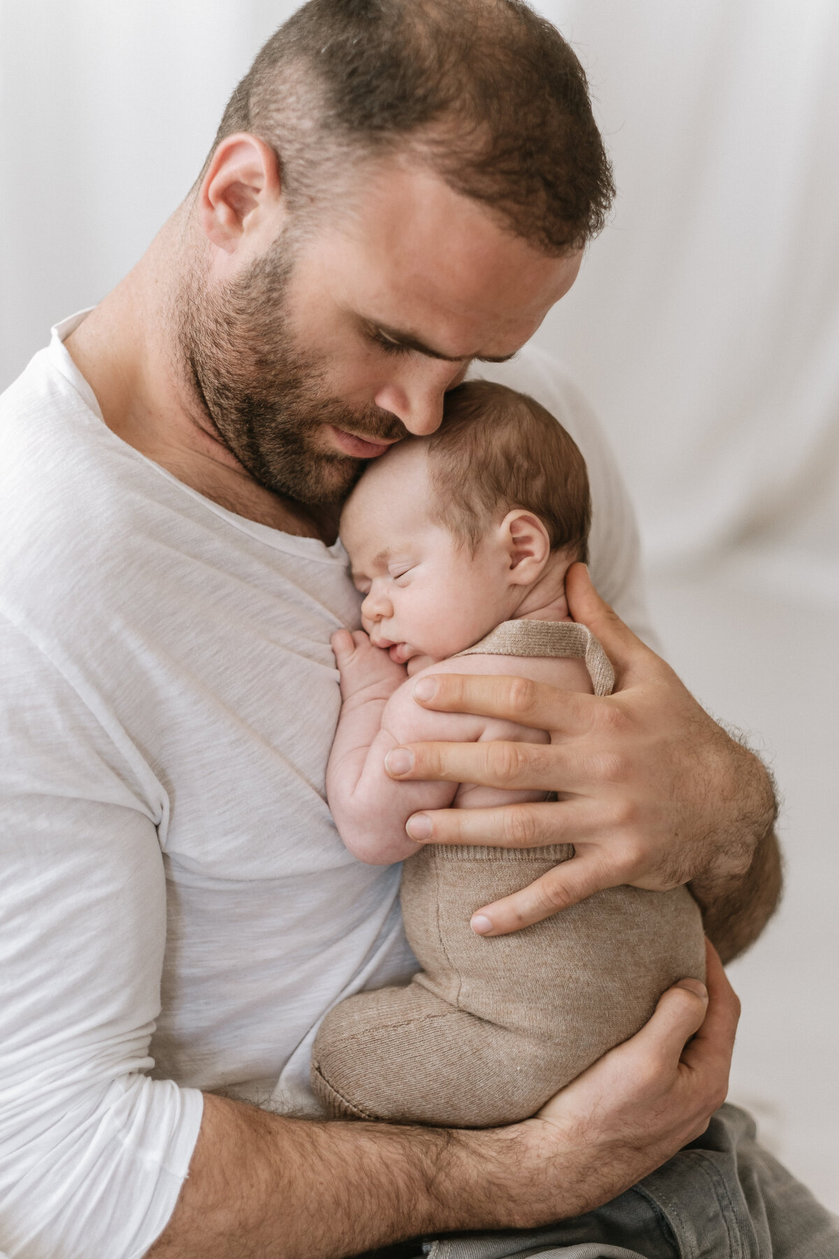 Father Jamie Roberts cuddles his newborn baby during a baby photoshoot in Bristol