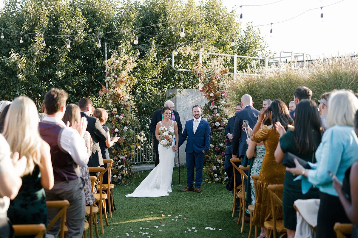 Broken Arch Ceremony Backdrop for fall Carolina’s wedding in Raleigh. Floral colors in mauve, cream, dusty pink, dusty blue, copper, and natural green. Floral accents of roses and fall color branches. Design by Rosemary and Finch Floral Design based out of Nashville, TN.