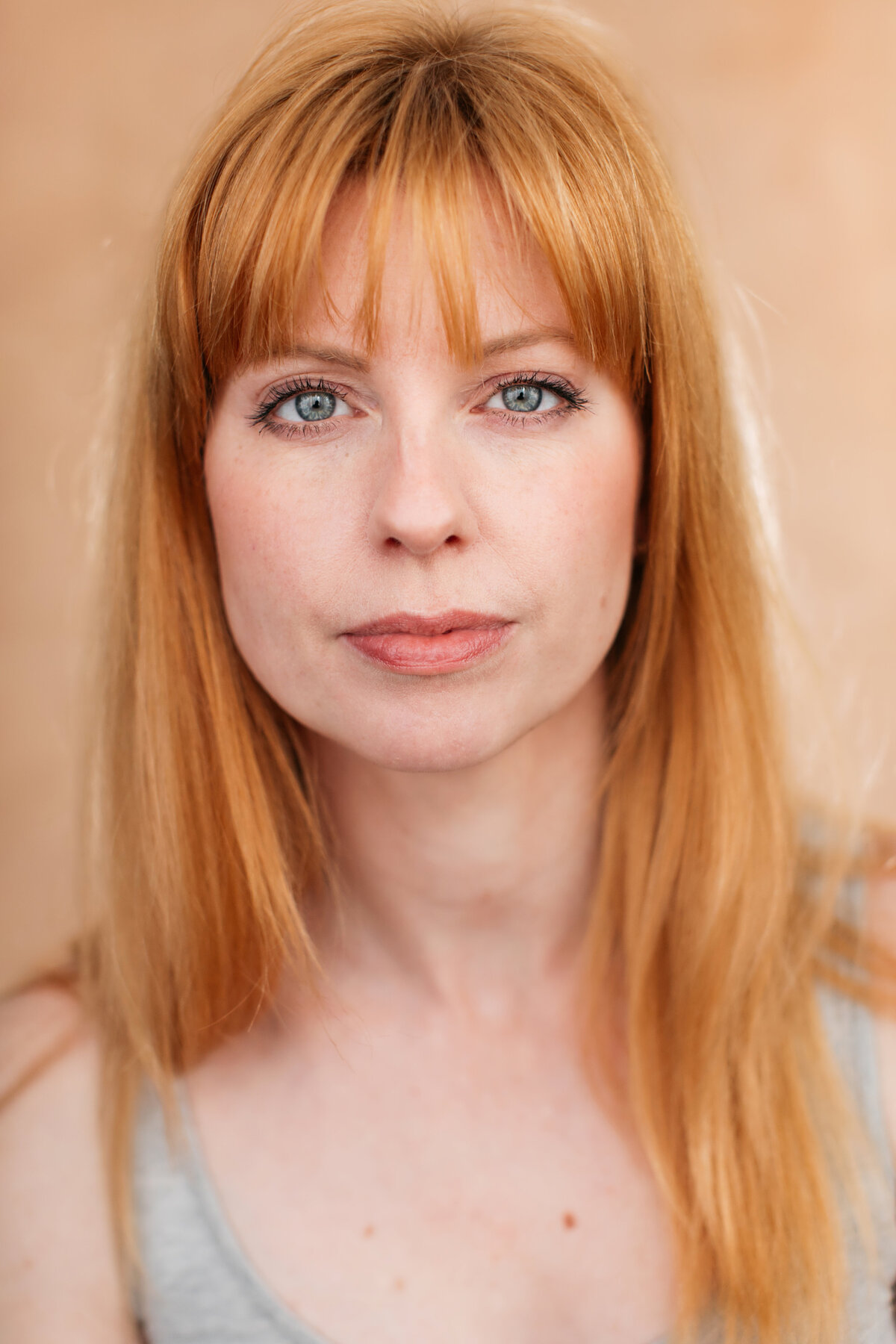 Castingfoto van Daphne Loeff. Roodharige vrouw met blauwe ogen voor een beige achtergrond.