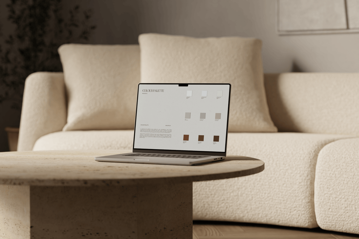 Laptop placed on a travertine coffee table with a cream bouclé sofa in the background, displaying a muted colour palette designed to create a refined and calming atmosphere.