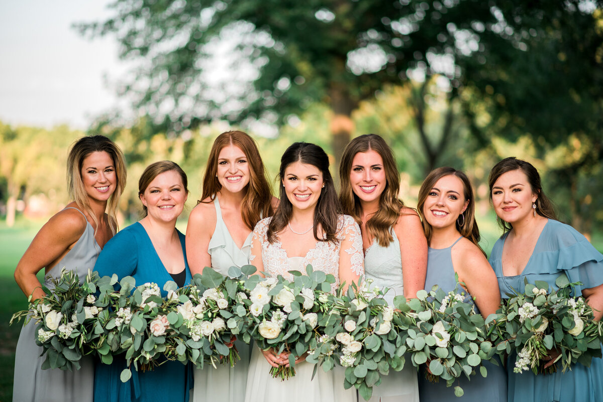 Bridesmaids with neutral flowers and alternating colors for dresses.