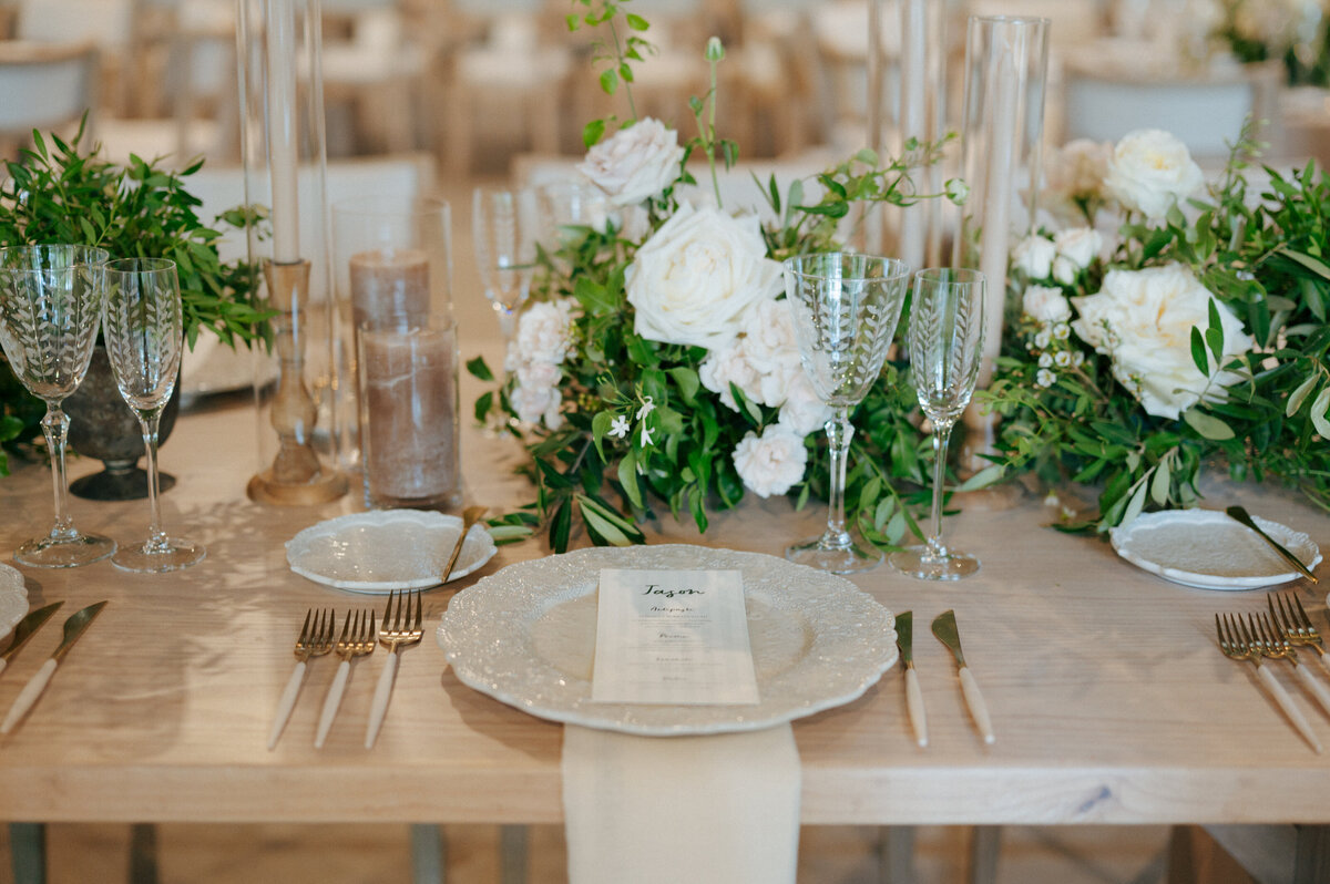 Reception table with white floral arrangements and greenery accents.