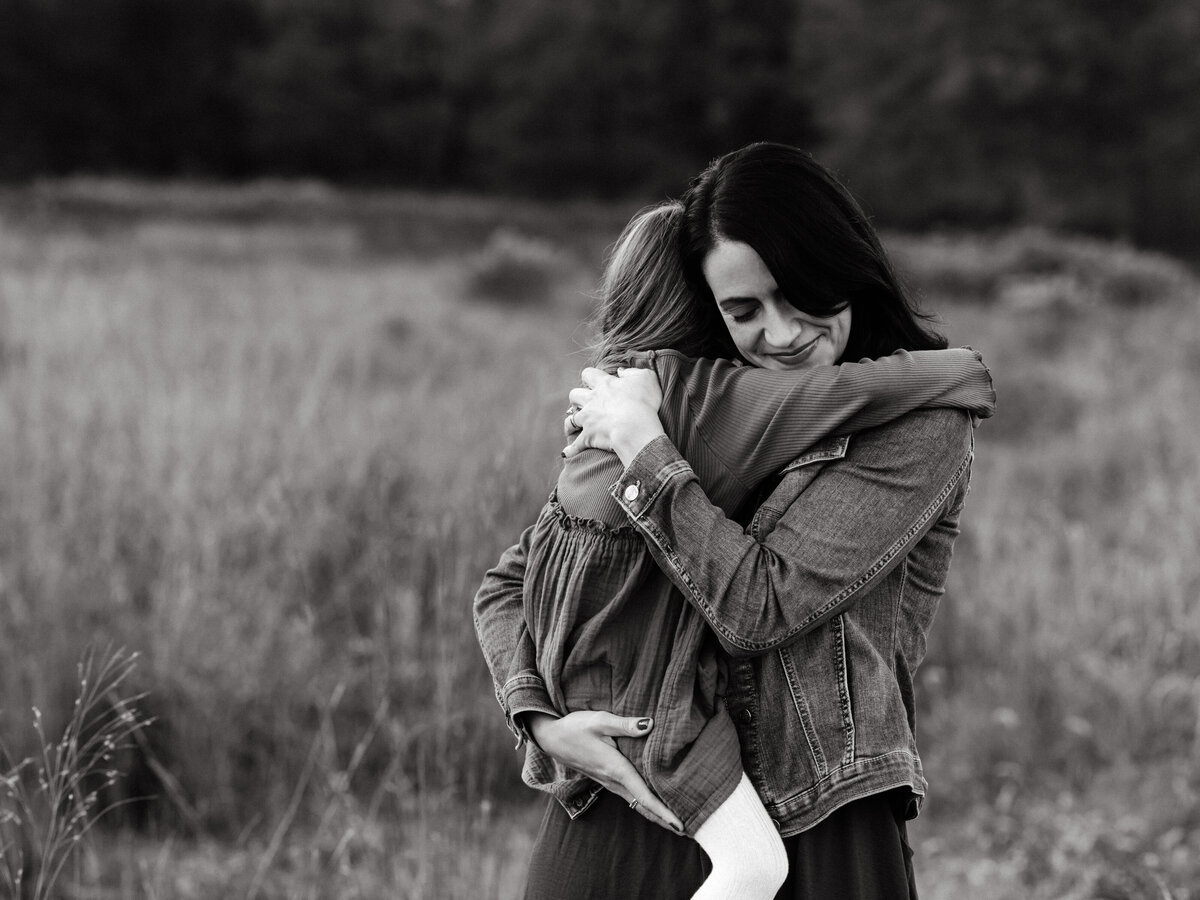 mom hugging daughter for family photos in field 