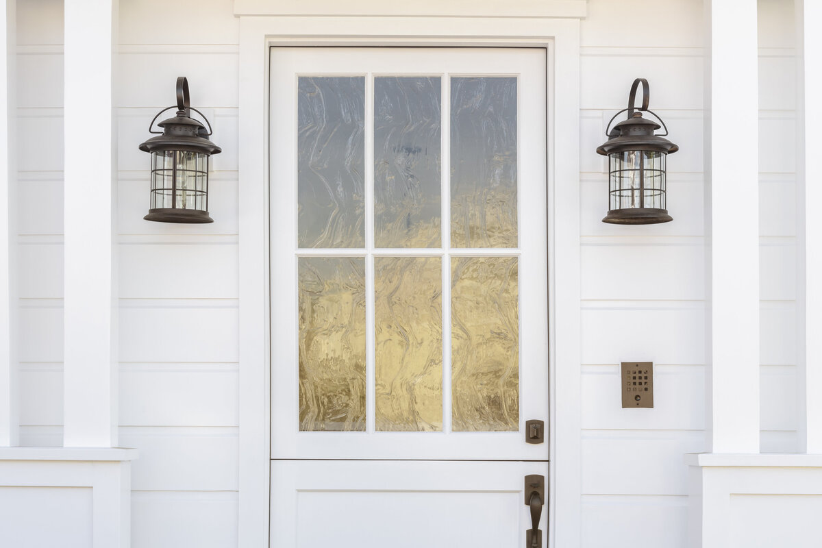 6 panel front door with rainwater privacy glass painted white surrounded by white siding and black lanterns 