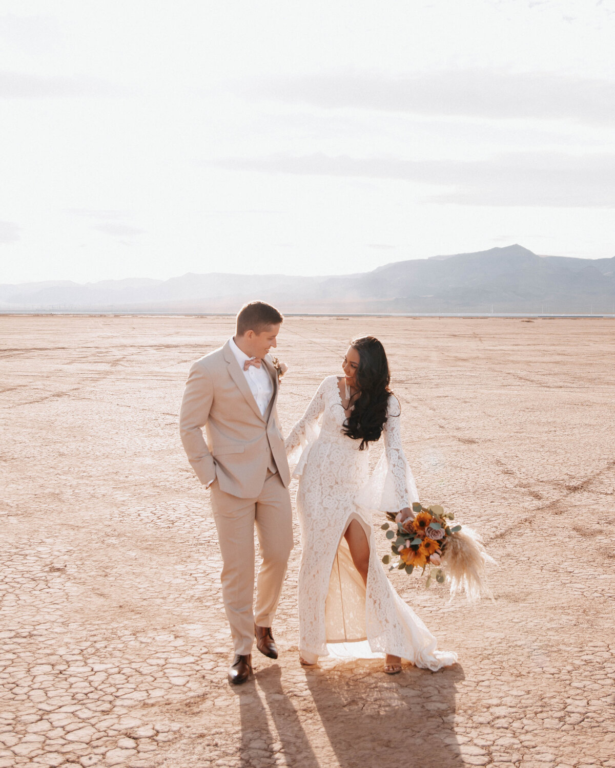 Newlywed couple on dry lake bed dancing for wedding photography