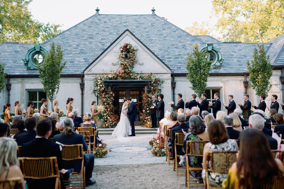 Organic growing floral installation for fall wedding ceremony backdrop. Private residence wedding build out for outdoor wedding ceremony and reception. Whimsical and organic floral design for autumnal wedding in colors of copper, yellow, blush, cream, and pops of orange. Clear tented wedding outside Nashville, TN. Design by Rosemary & Finch Floral Design in Nashville, TN.