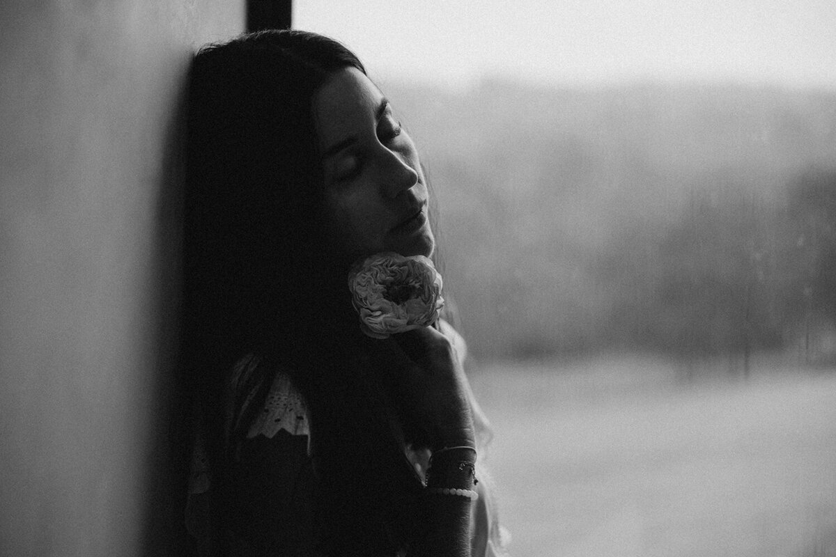 A moody black-and-white portrait of a woman holding a flower, styled by a Sunshine Coast branding photographer to highlight emotional depth.