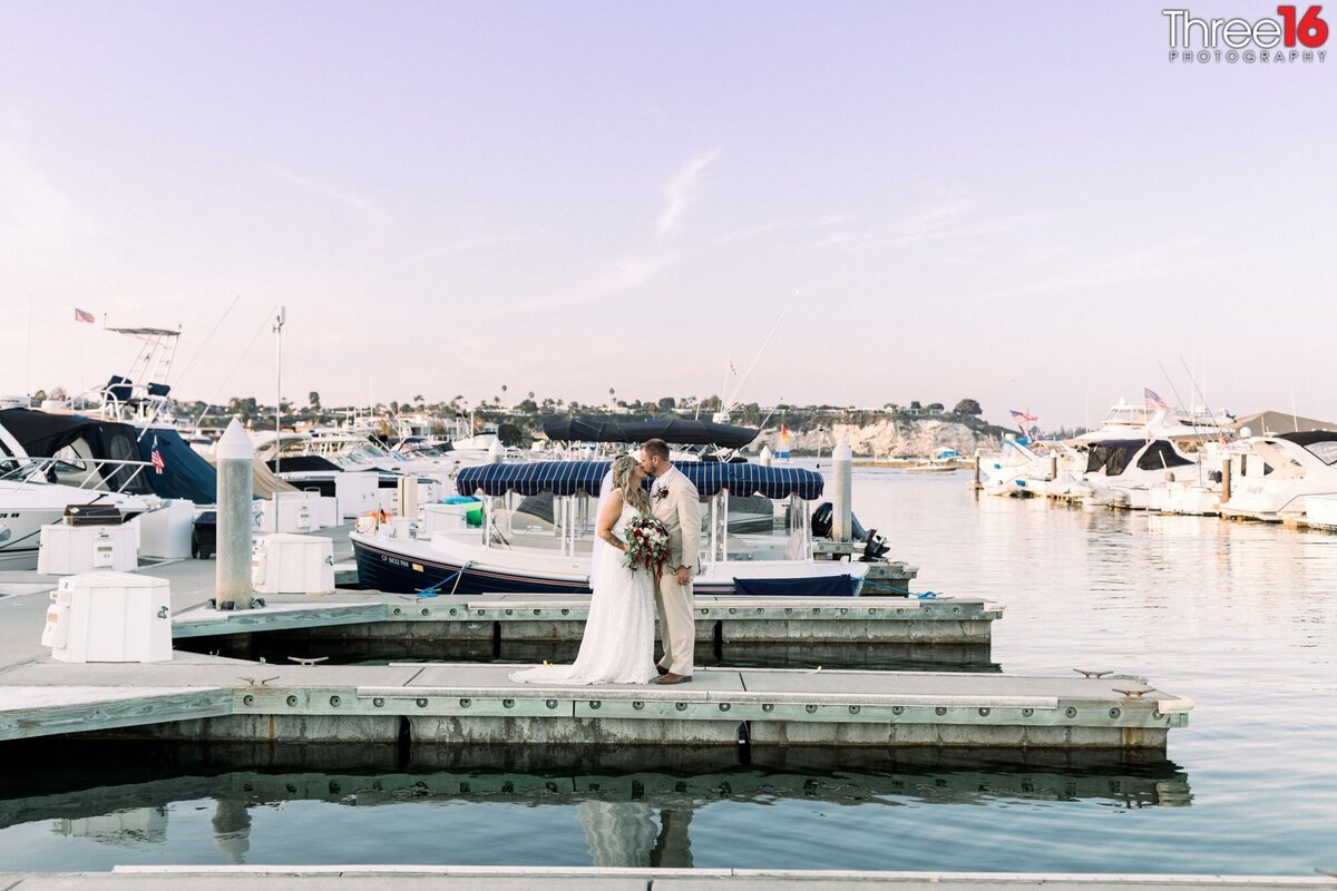 Bride and Groom share a kiss while standing on the docks of the Newport Back Bay