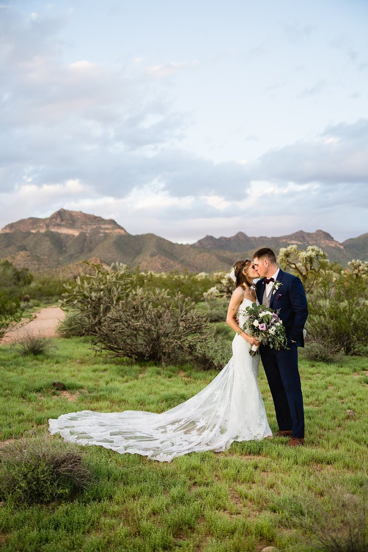 Bride and groom kissing in the desert at their Superstition Manor wedding by PMA Photography.