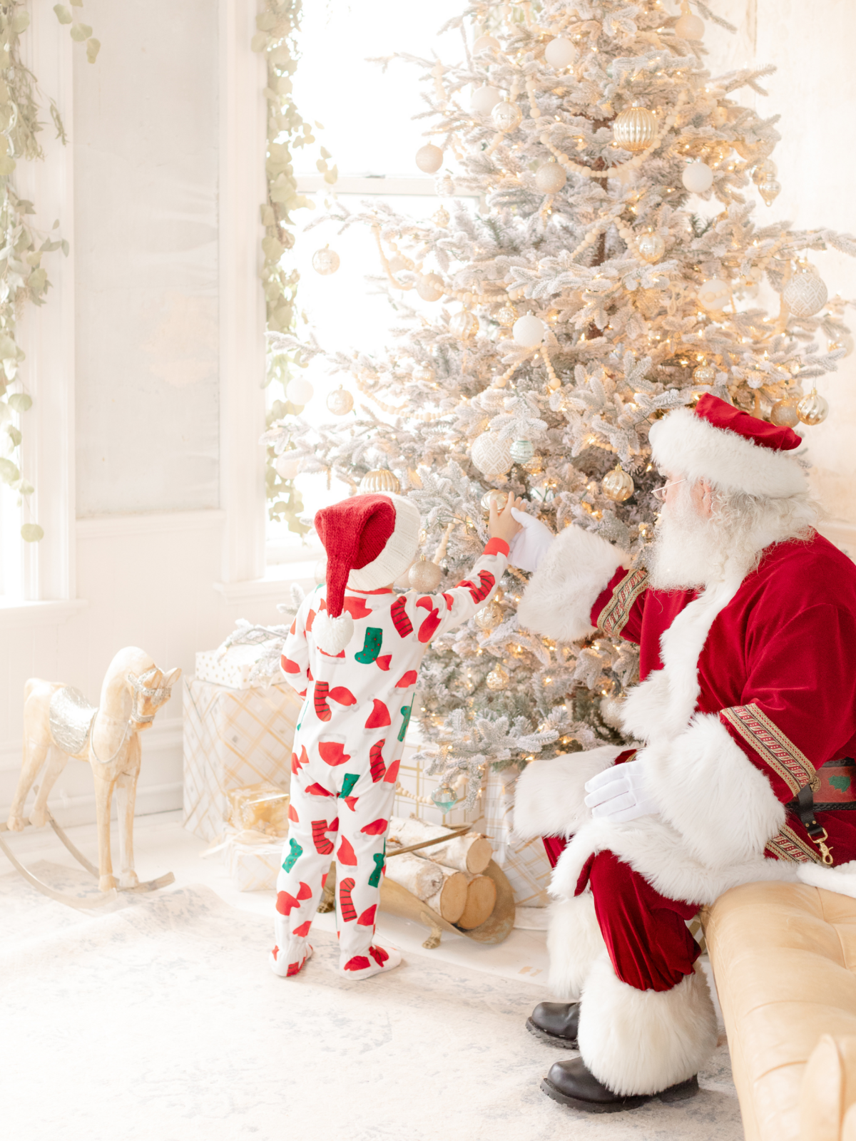 boy wearing christmas pajamas decorates tree with santa claus