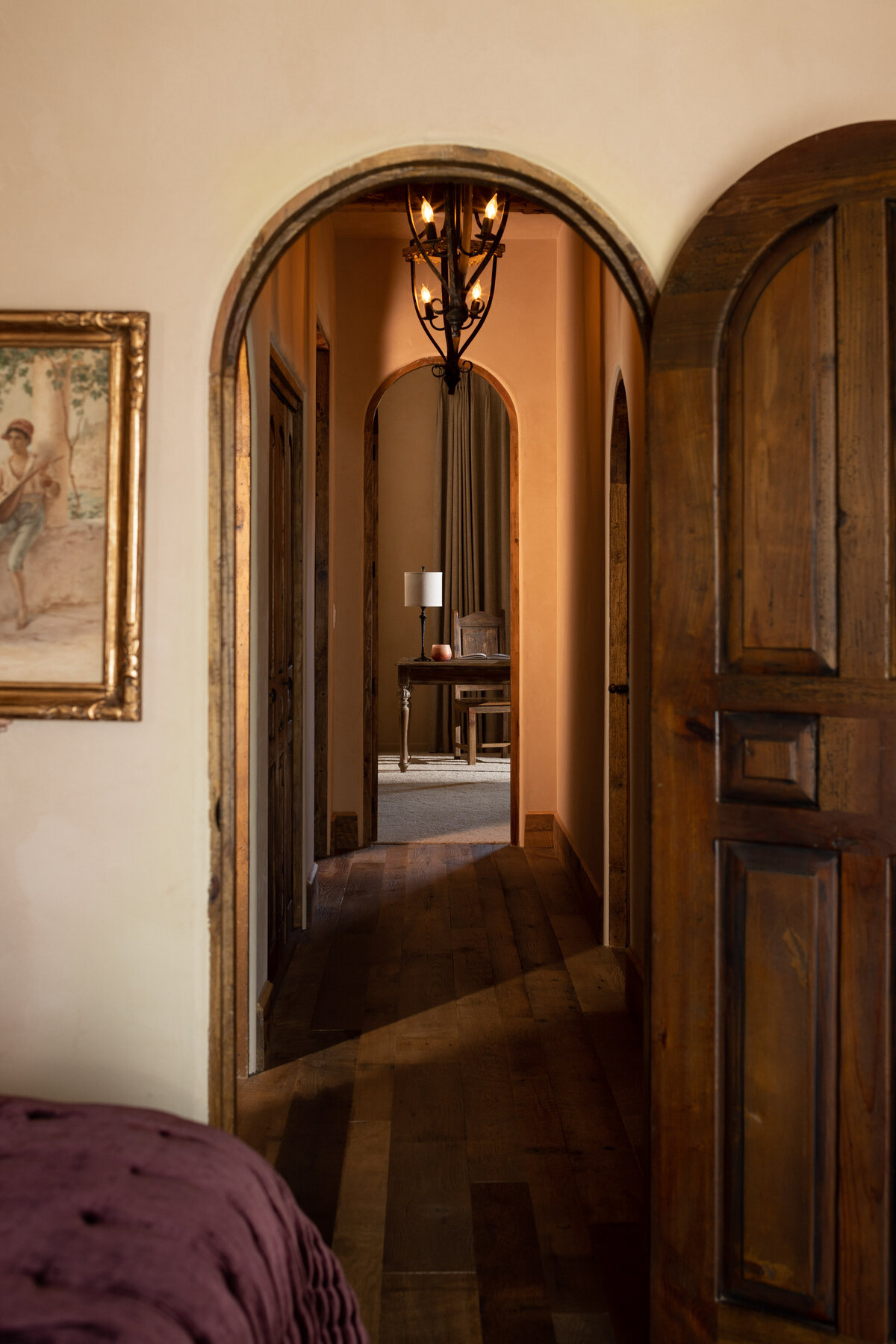 Interior photography of a rustic hallway with arched doors and warm lighting