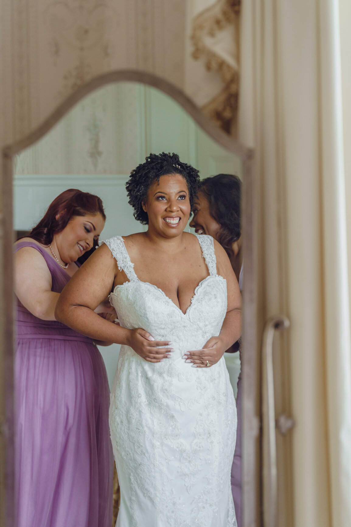 Bride is helped into gown by her mother and maid of honor at Belmont Country Club.