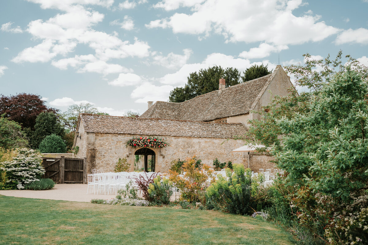 Outdoor summer wedding ceremony at Caswell House with white chairs and bright sunshine