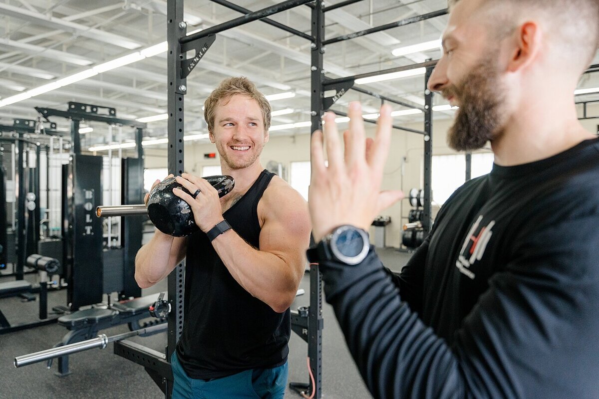 Columbus personal training branding photos with trainer helping client exercise with a kettle bell photographed by brand photographer