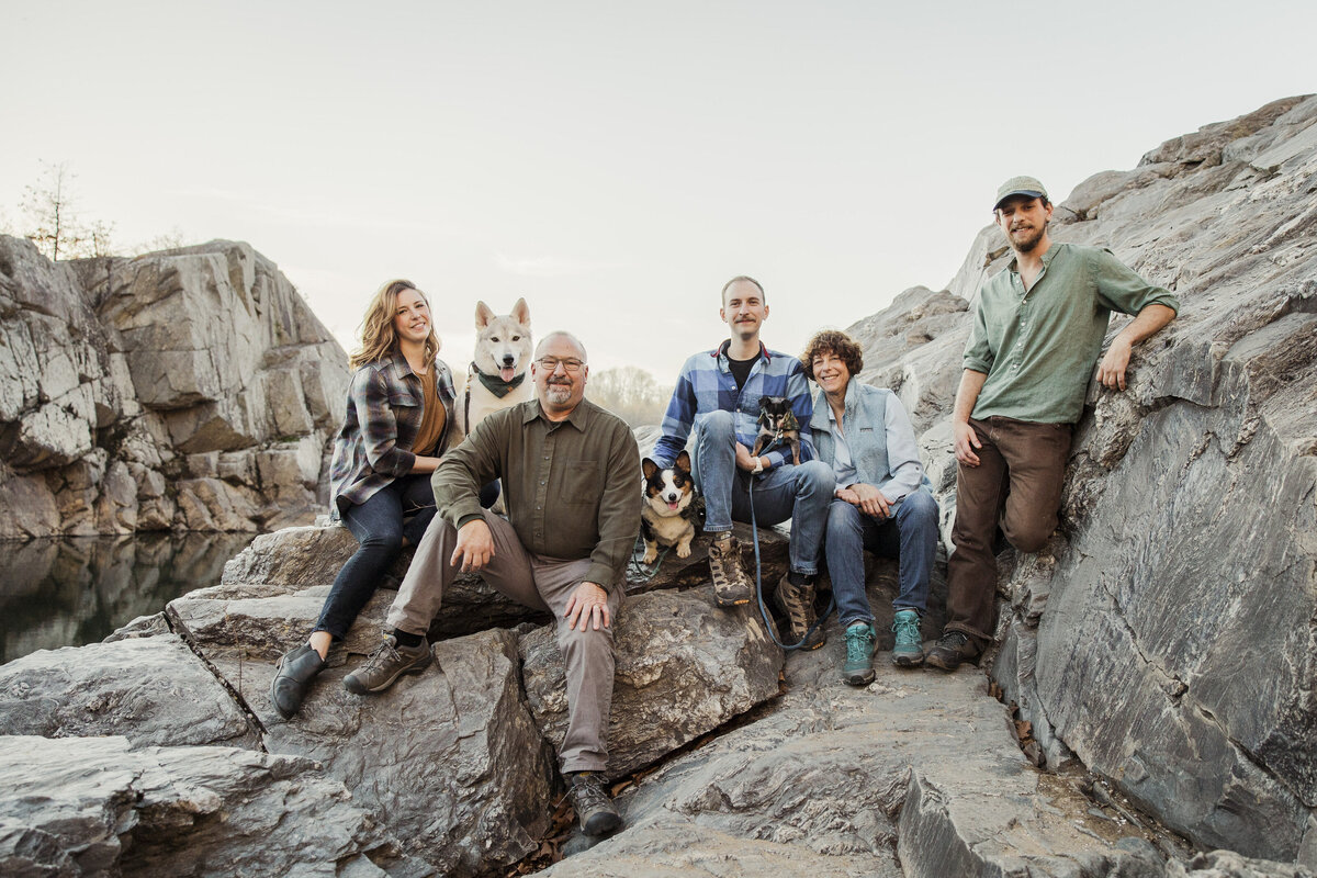 Family members sit on rocks with their pups.